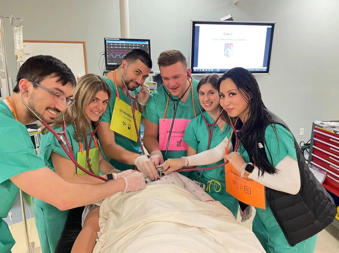 Medical students training on mannequin in simulation lab.