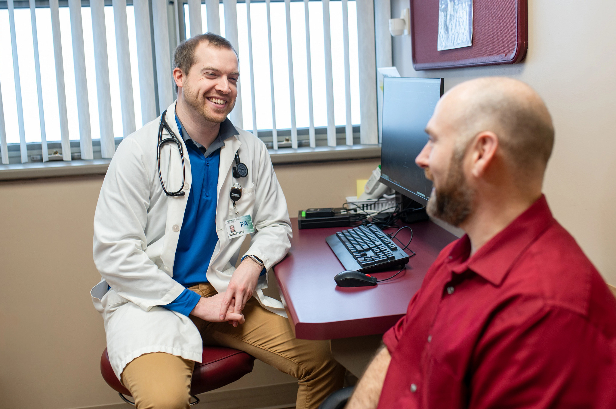Gundersen physician assistant smiling and seated across from patient in exam room.