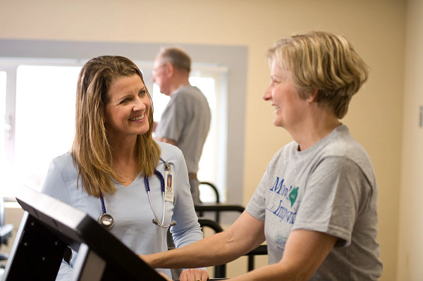 Exercise physiologist helping female patient on the treadmill.