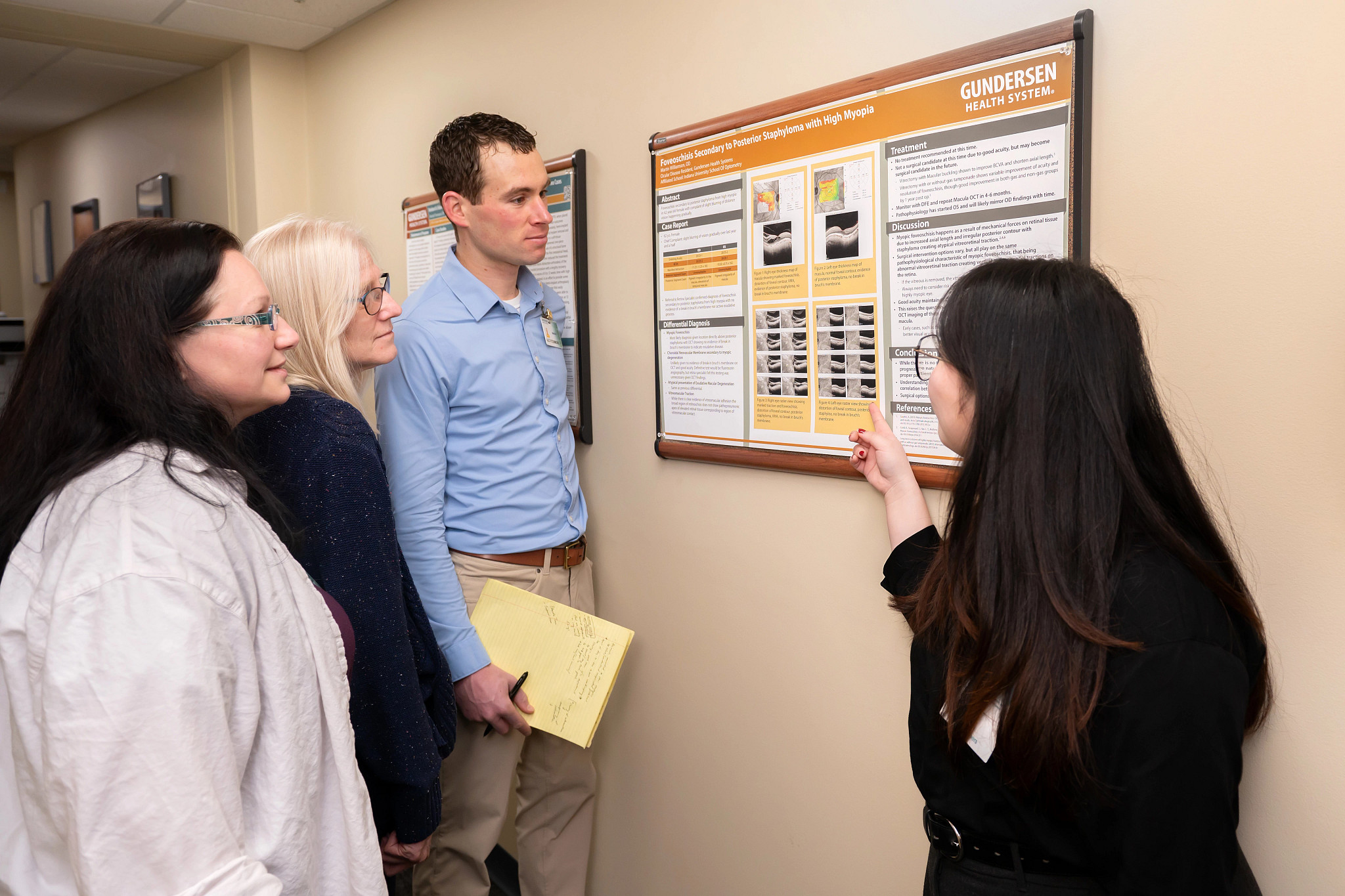 Four researchers looking at research poster on the wall and reviewing results.