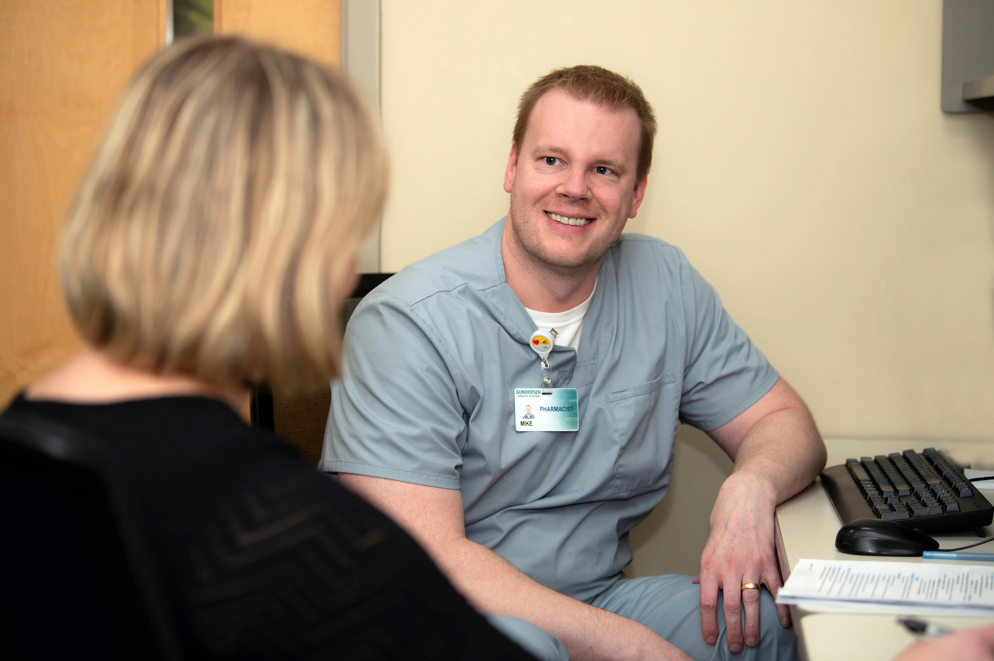 Pharmacist seated at desk helping patient.