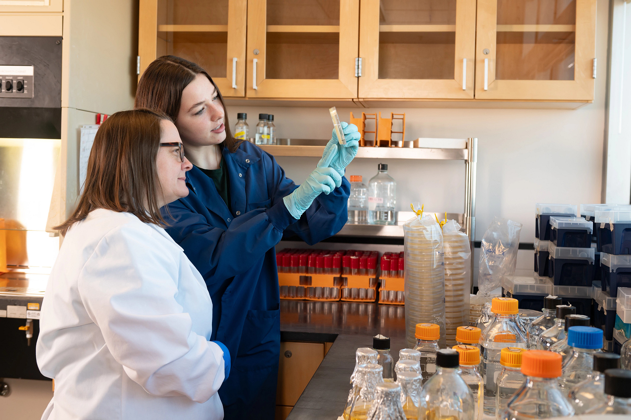 Two female research scientists examining specimen slide.