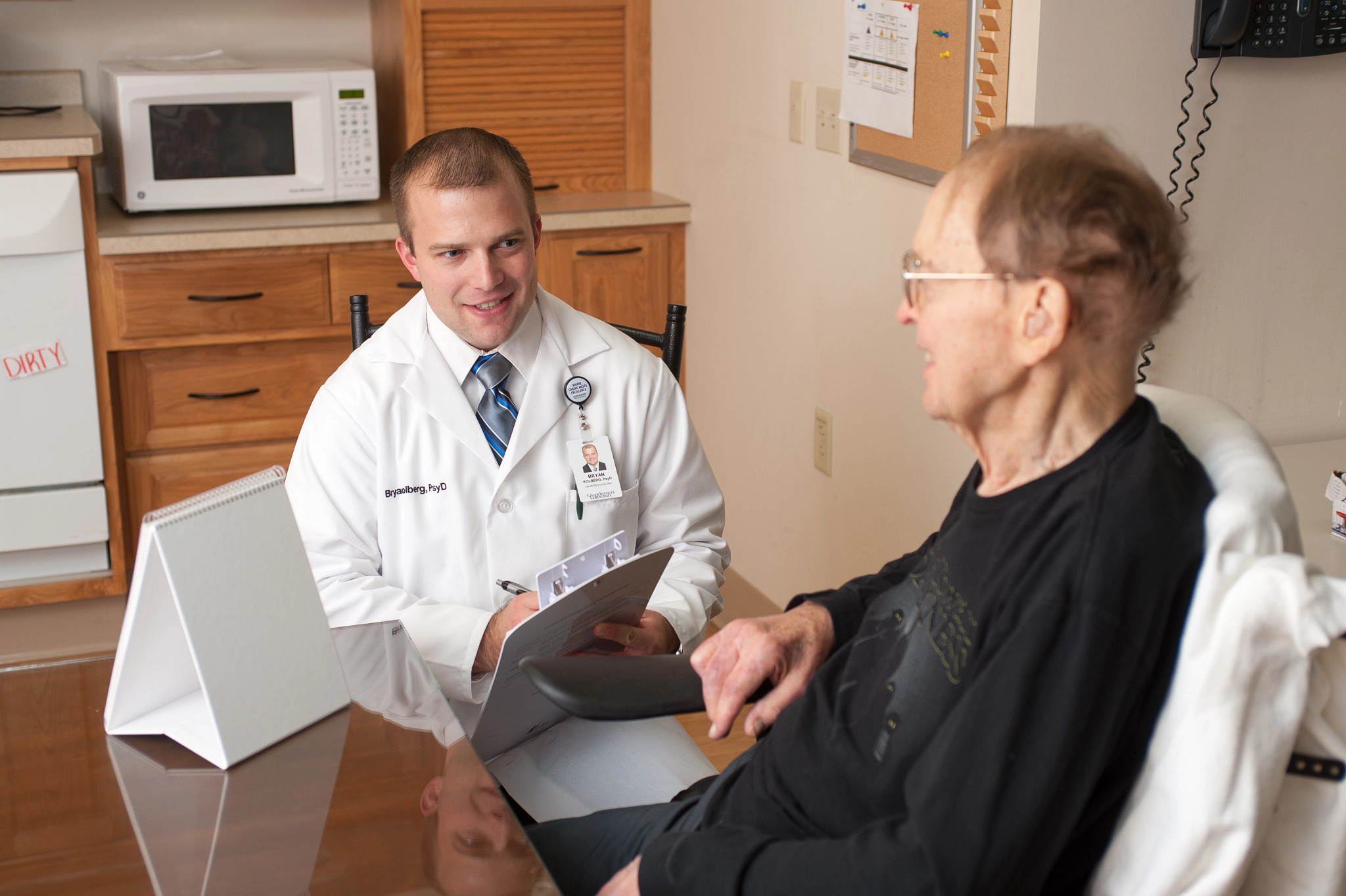 Psychologist speaking with patient in bed.