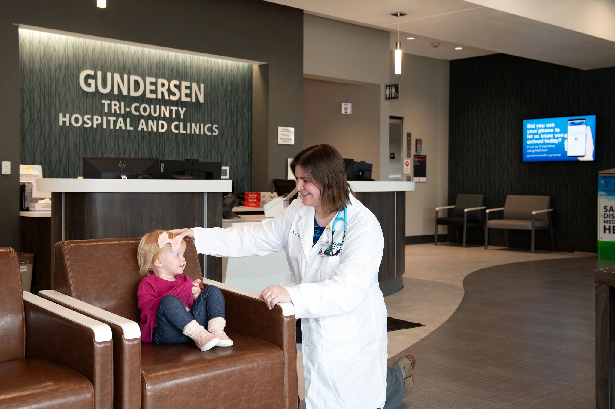 Gundersen Tri-County physician with toddler in hospital lobby.