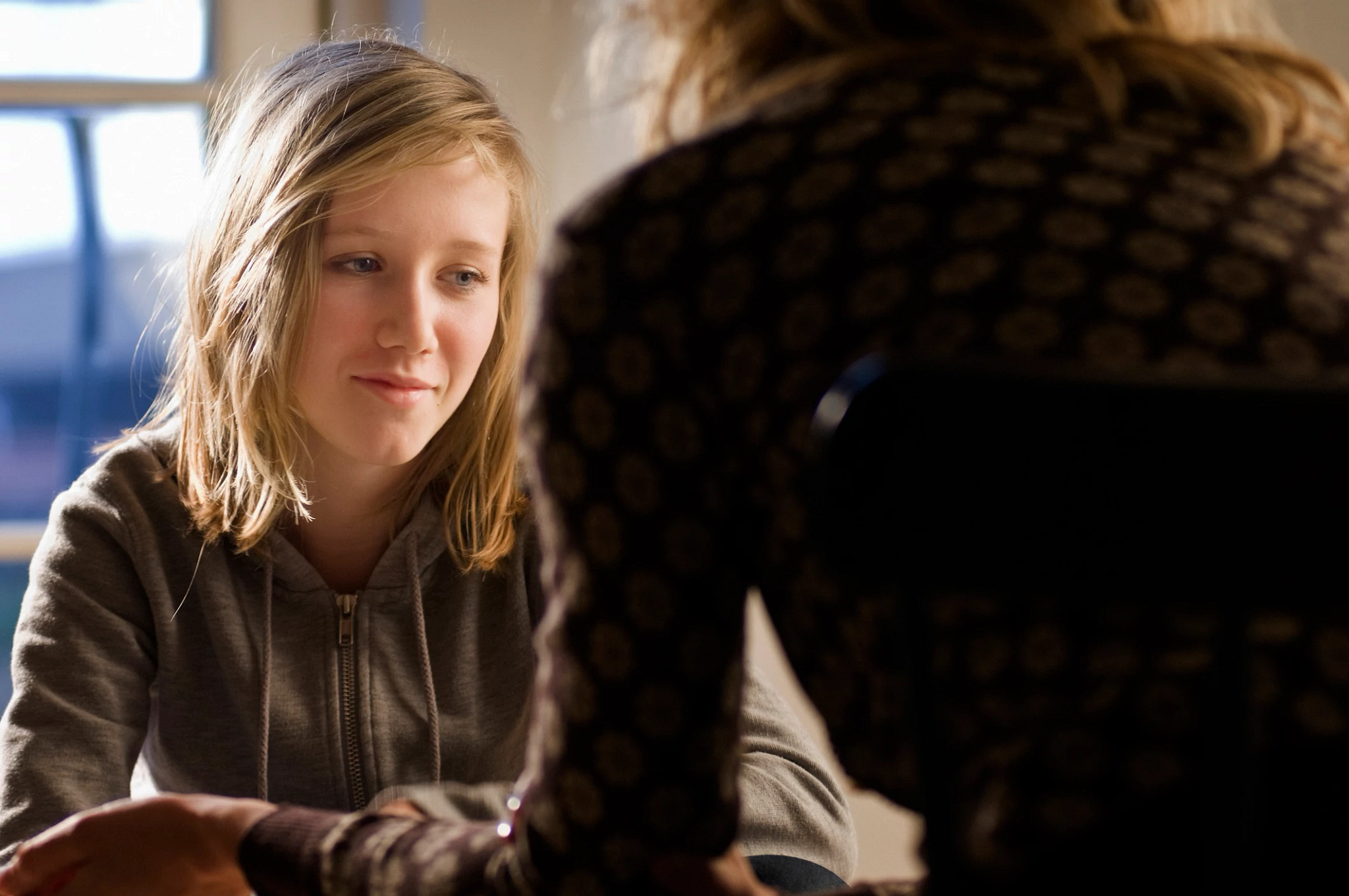 Adolescent girl talking to therapist in office setting.