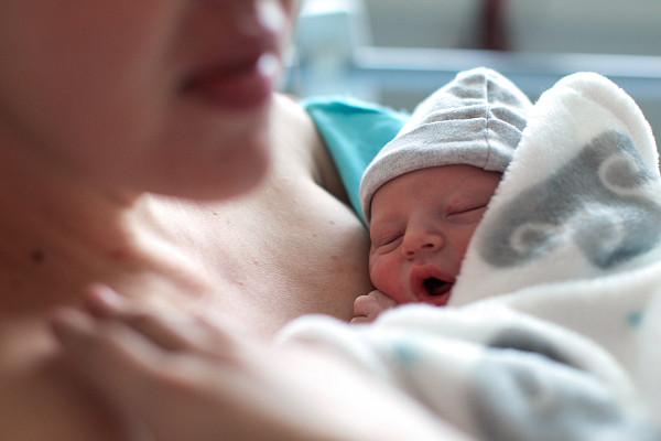 A newborn baby boy breastfeeding for the first time in hospital, directly after a caesarean section