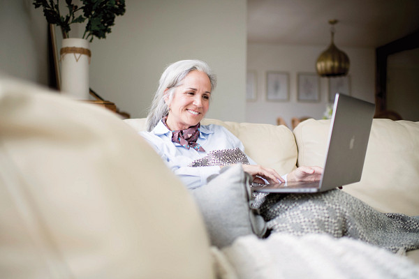 Senior woman looking at laptop while seated on a couch.