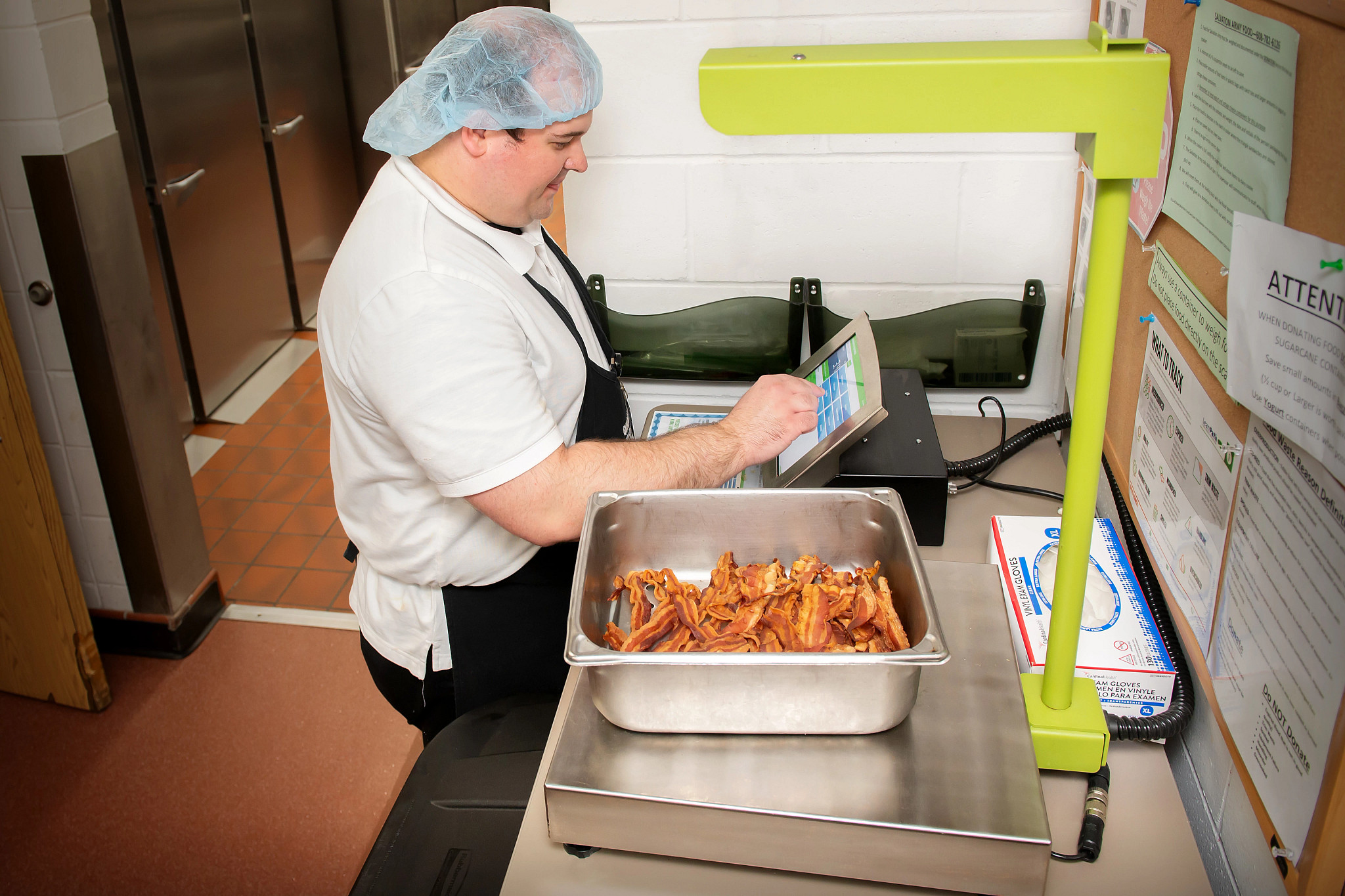food service employee using electronic food waste tracking program called LeanPath