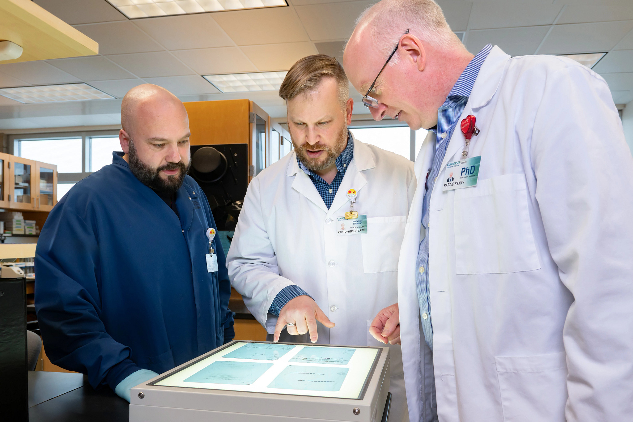 Three male cancer research scientists working together in the laboratory.