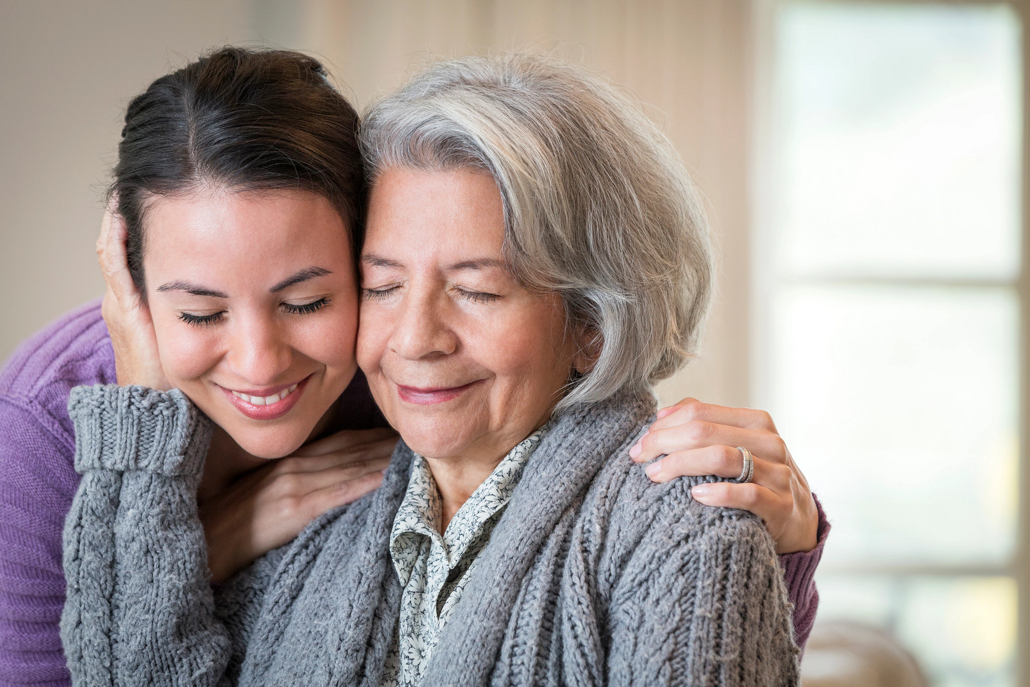 Close up of smiling mother and daughter hugging.