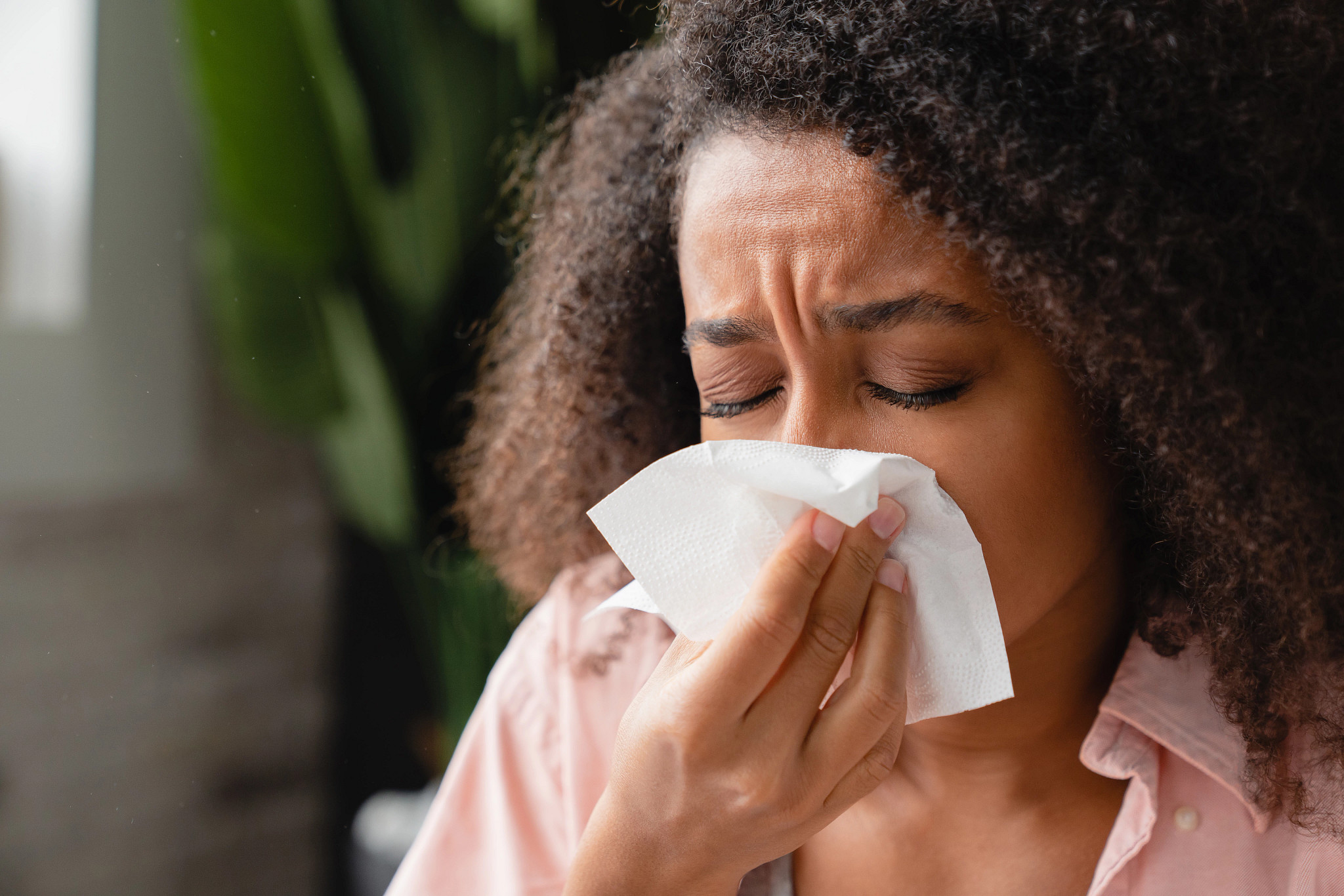 Sneezing ill young woman using tissue