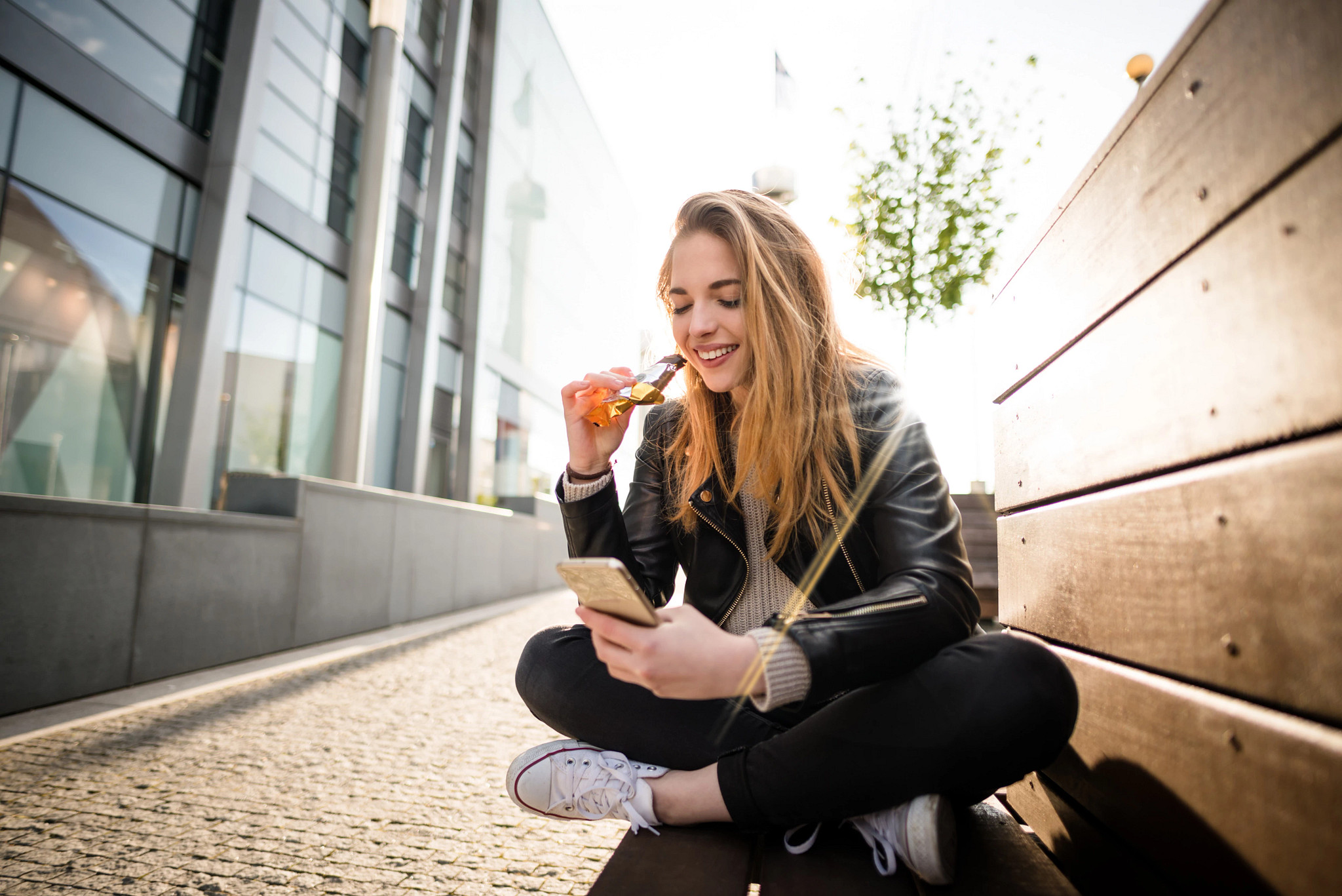 Teenager eating chocolate on phone outddoor in street.