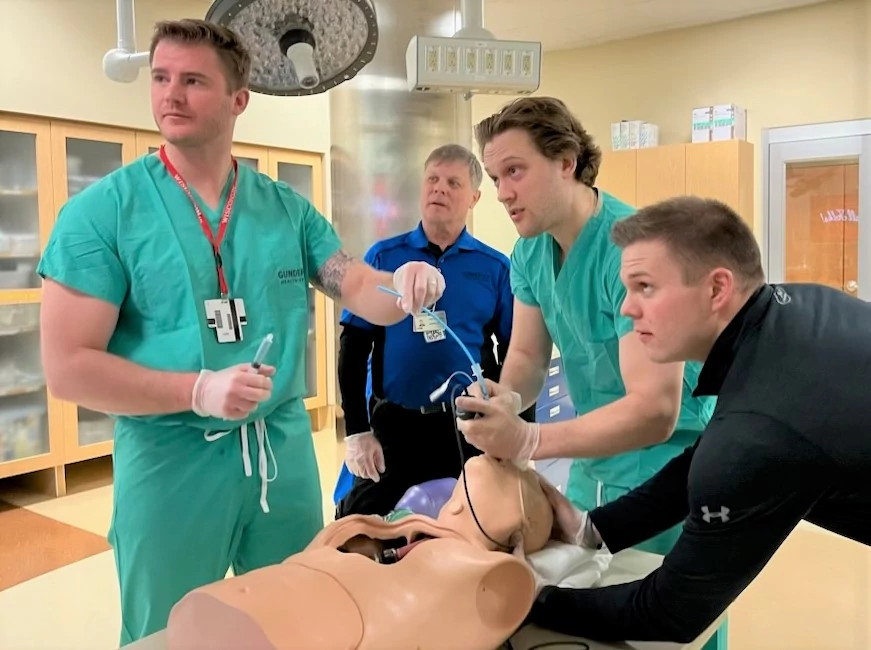 Medical students examining patient airway in simulation lab.