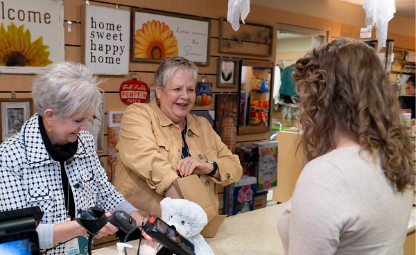 Gundersen Gift Shop volunteers helping customer at check-out counter.