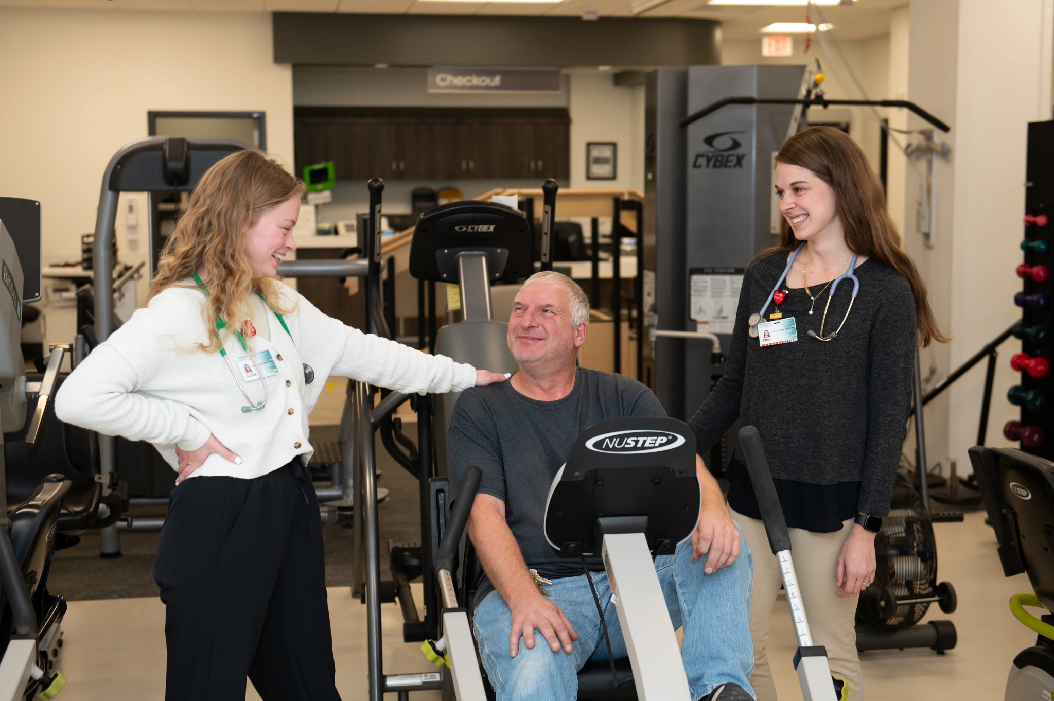 Gundersen Tri-County therapists smiling alongside patient in therapy gym.