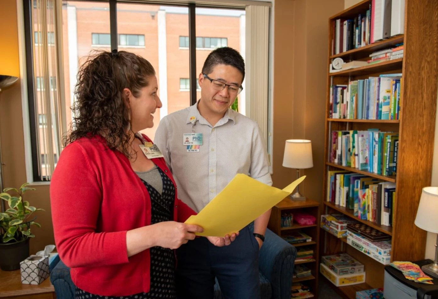 Two psychologists discussing patient file in office.
