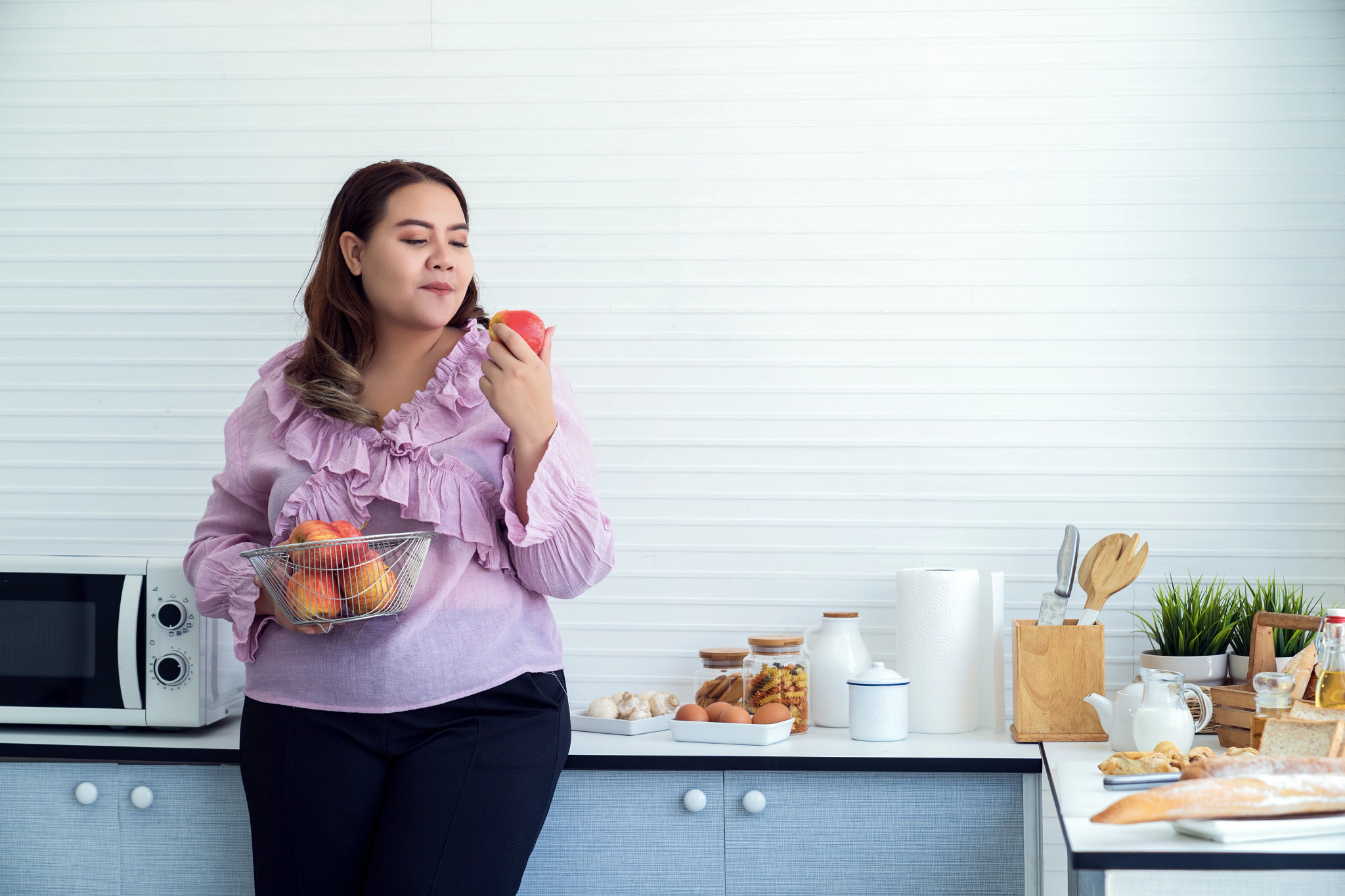 woman eating an apple in her kitchen at home
