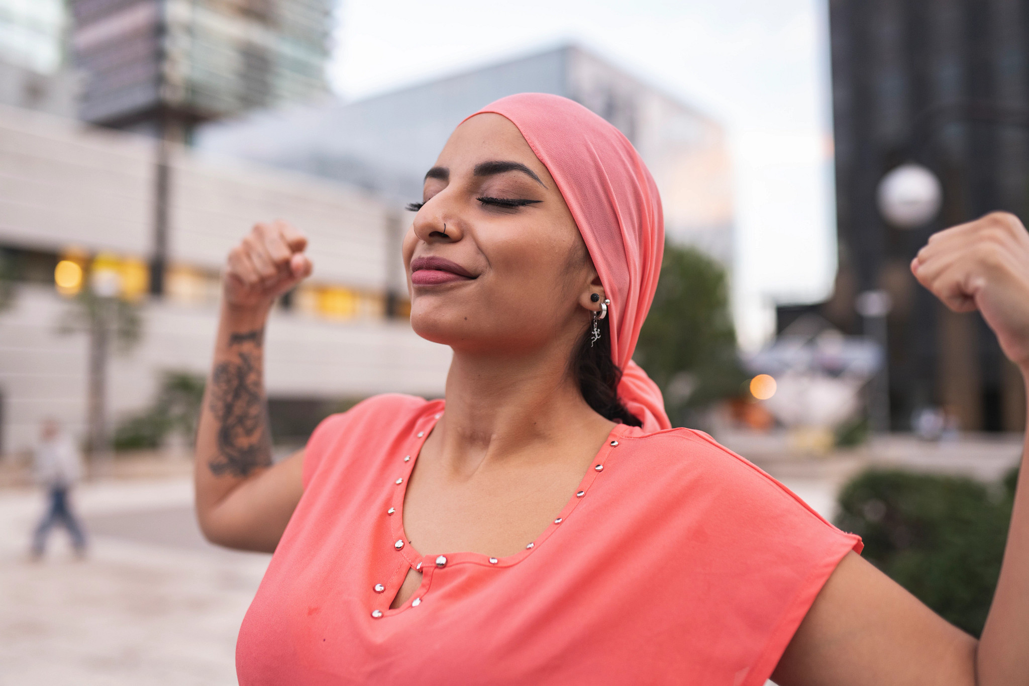 Woman wearing pink with raised arms showing muscle.