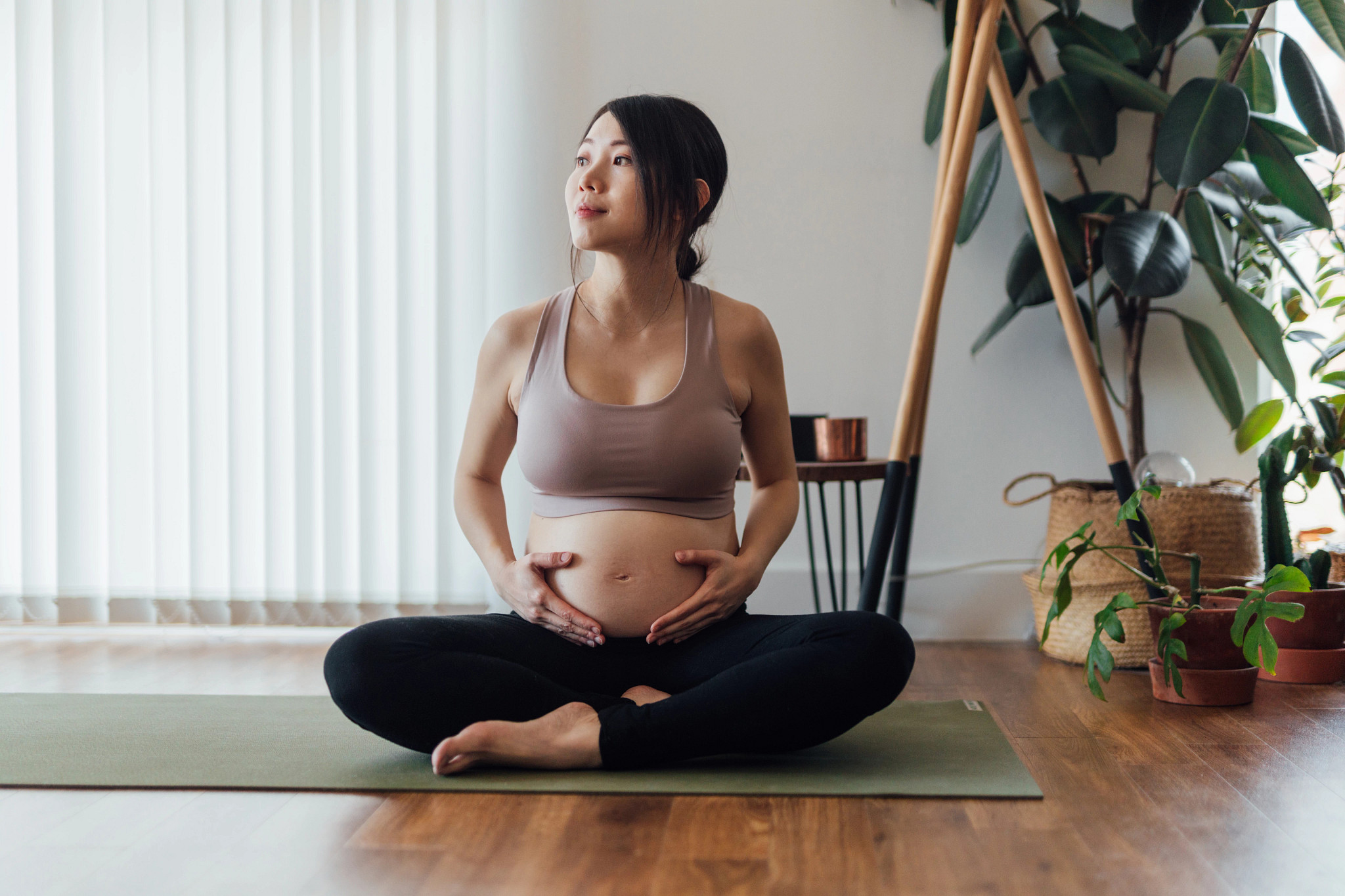 Beautiful young Asian pregnant woman resting after doing pregnancy yoga at home.
