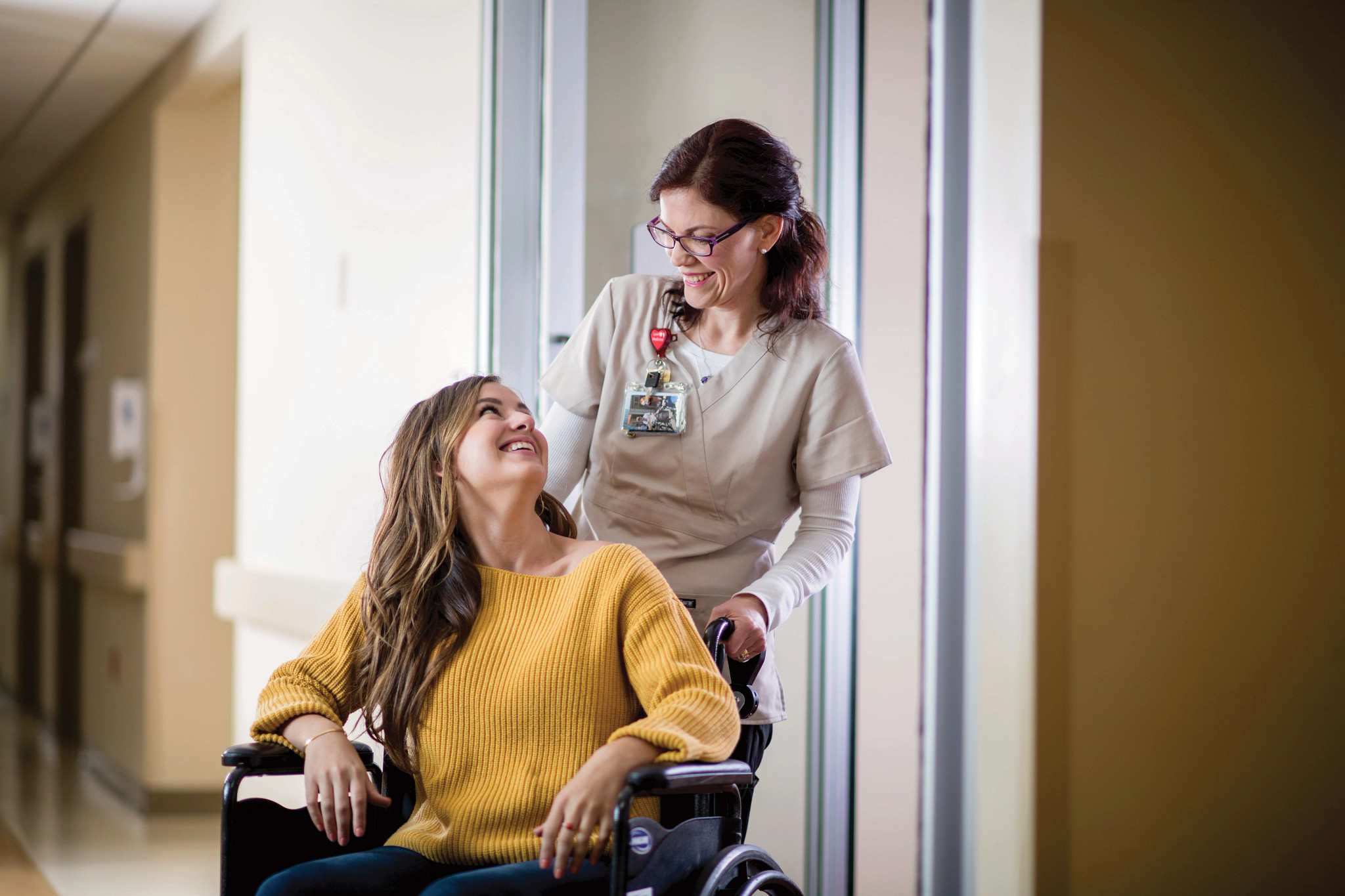 Female nurse pushing adult female patient in wheelchair.
