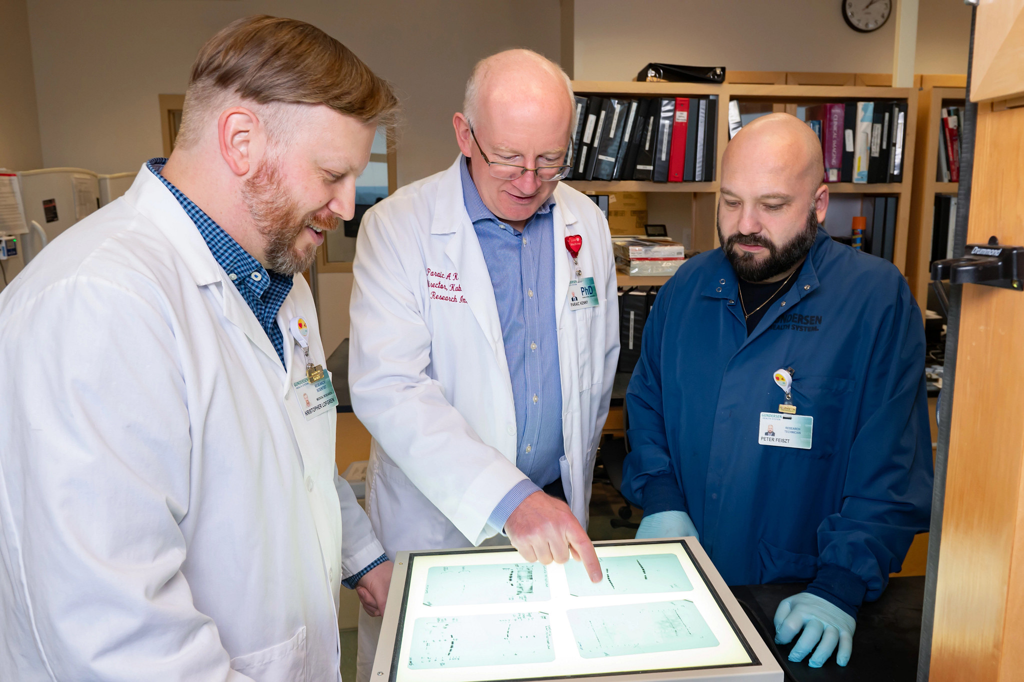 Three cancer research scientists looking at study data in lab.