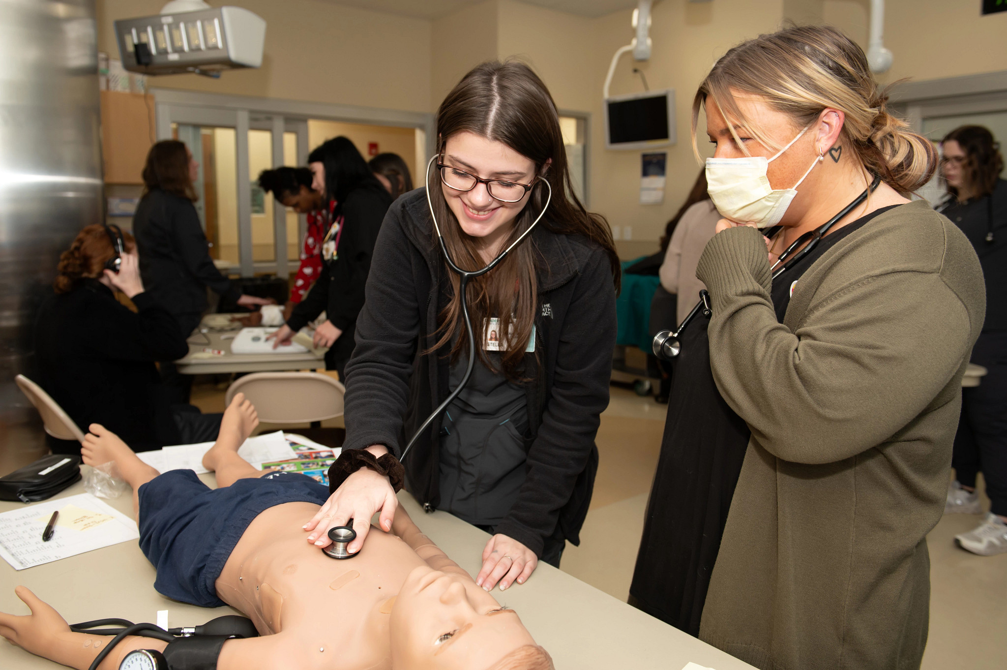 Female medical assistant trainees working on dummy.