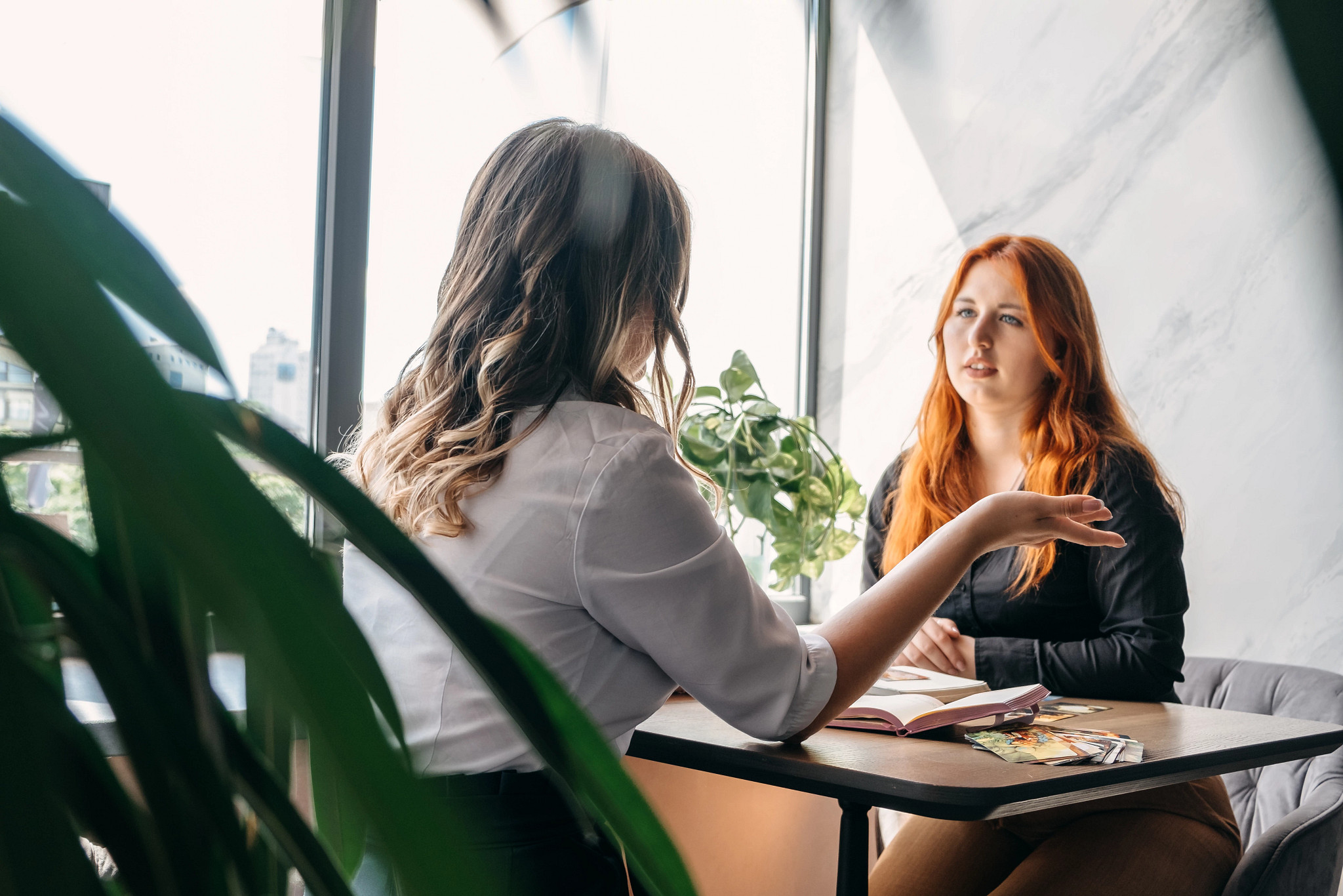 Young woman talking to a mental health professional while seated at a table.