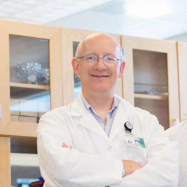 Gundersen Research Institute cancer researcher Pariac Kenny smiling in white lab coat.