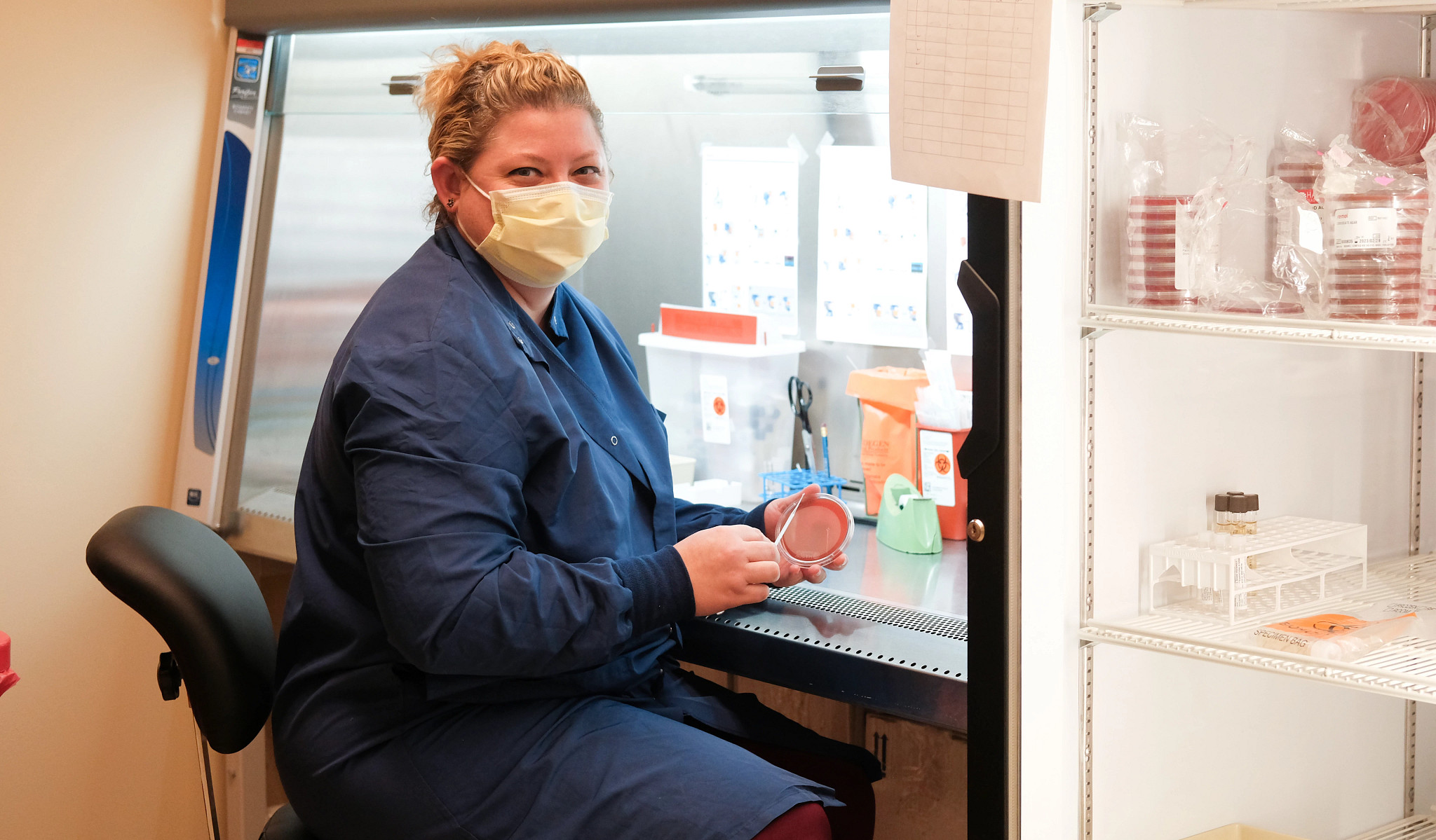 Lab tech working at station and smiling.