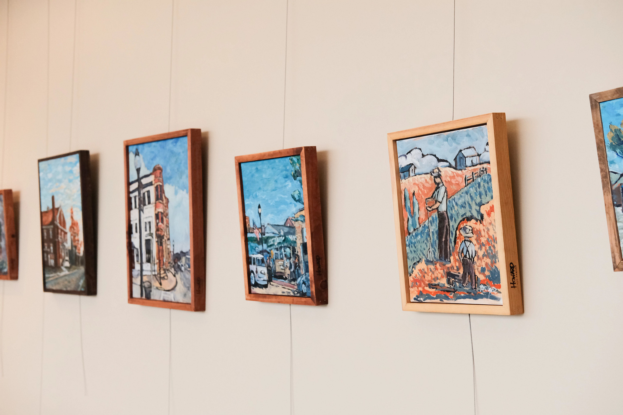 Paintings of rural scenery hanging in hospital art gallery.