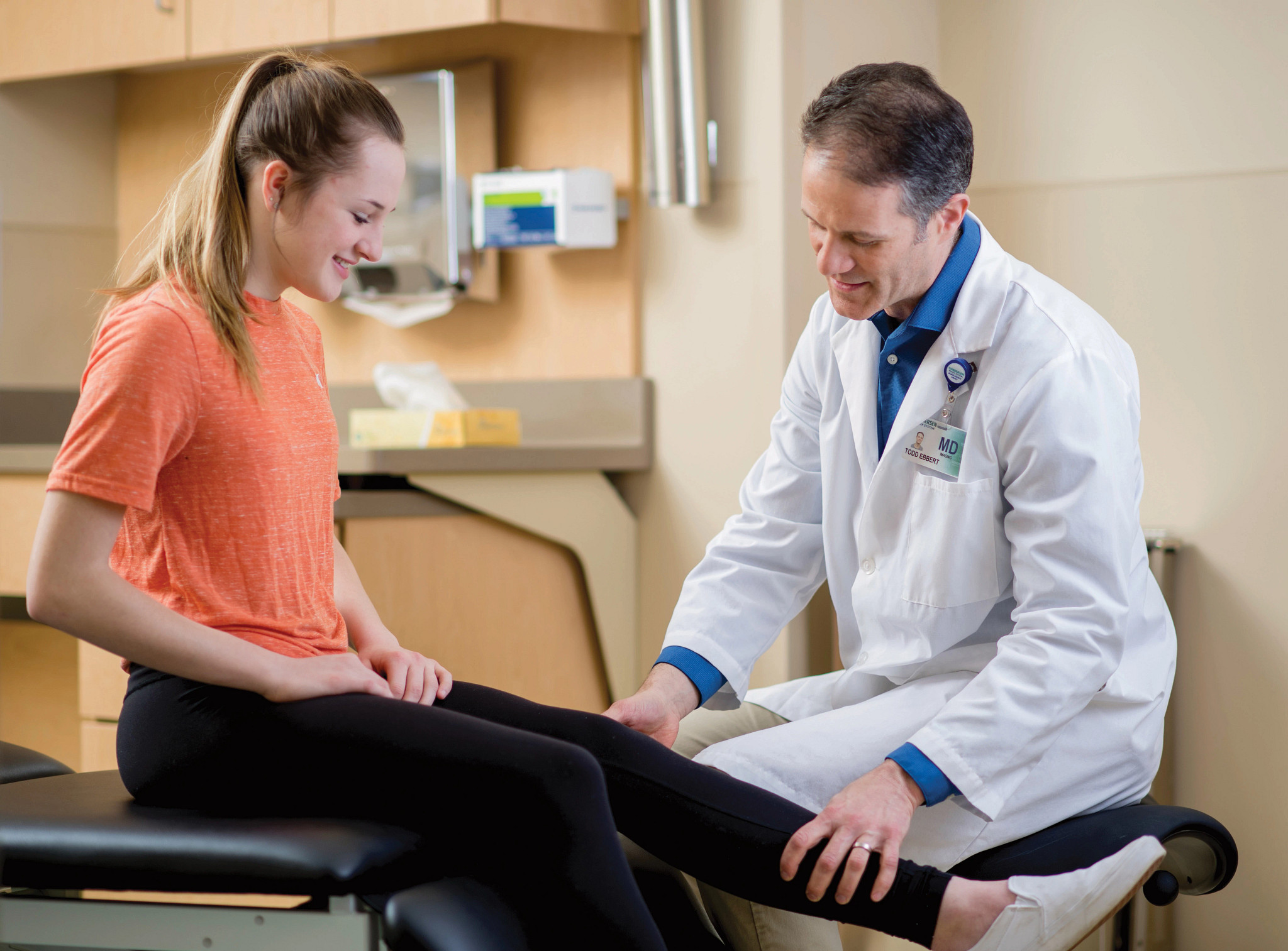 Adult male doctor examining teenage girls knee.