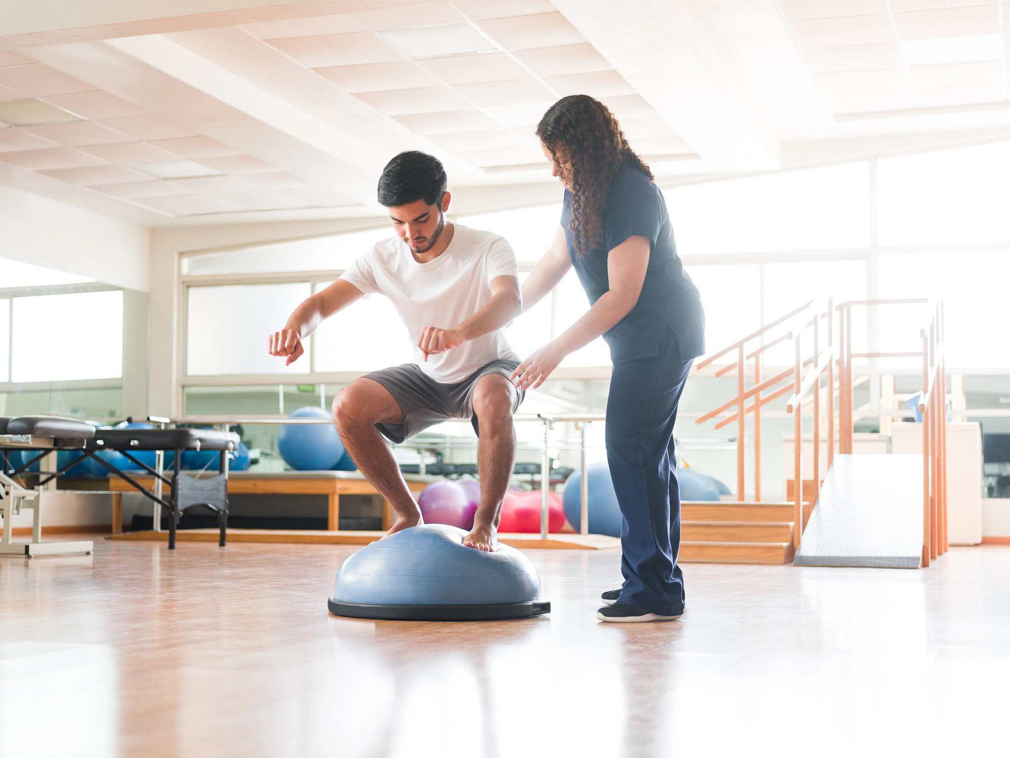 Male athletic patient standing on balance ball
