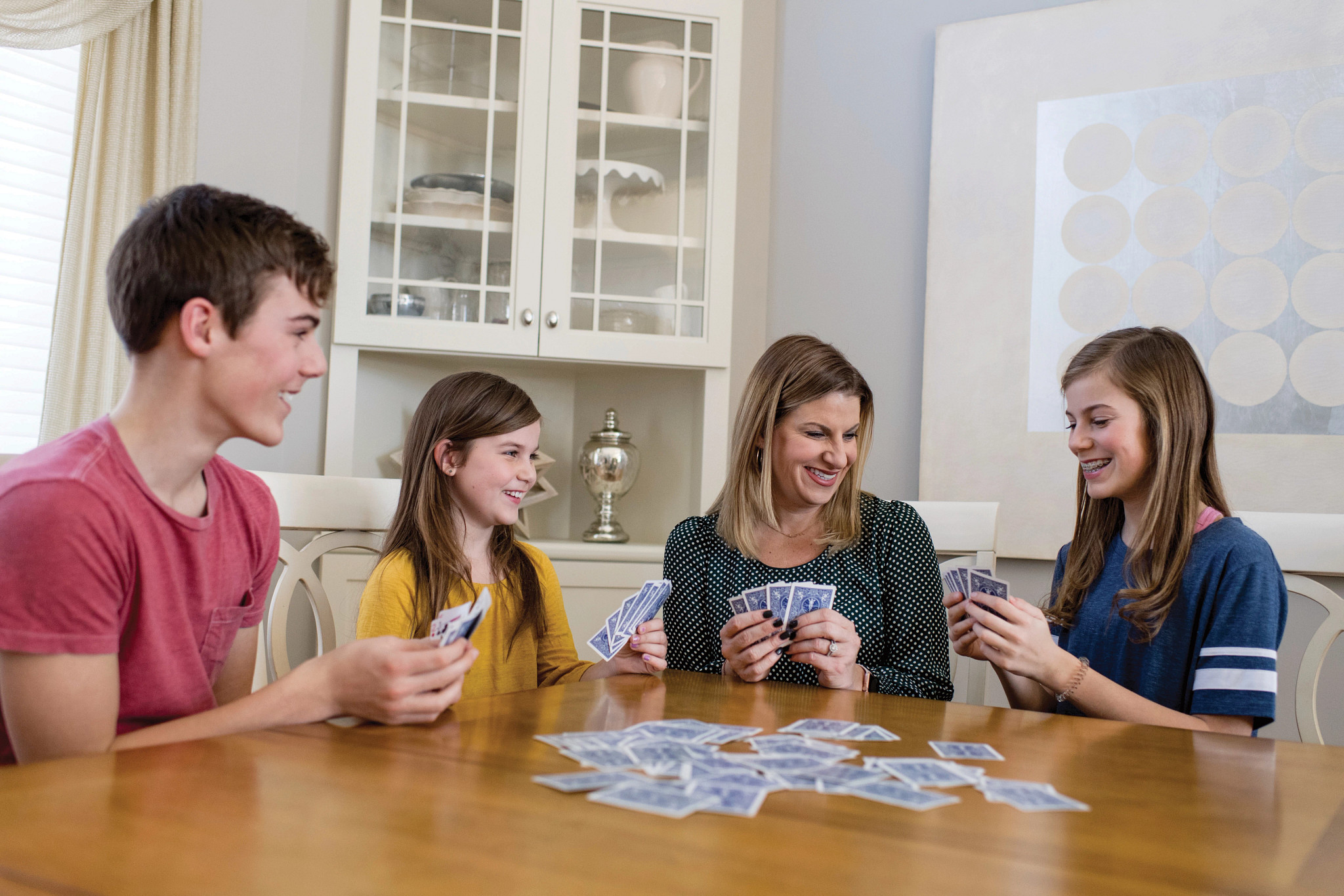 Young teenage family playing cards at a table.