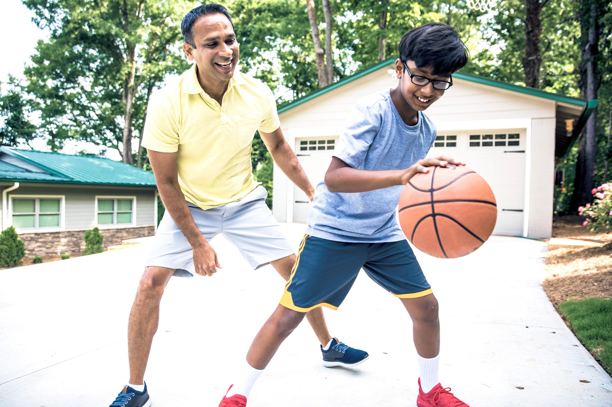 Father and son playing basketball in driveway