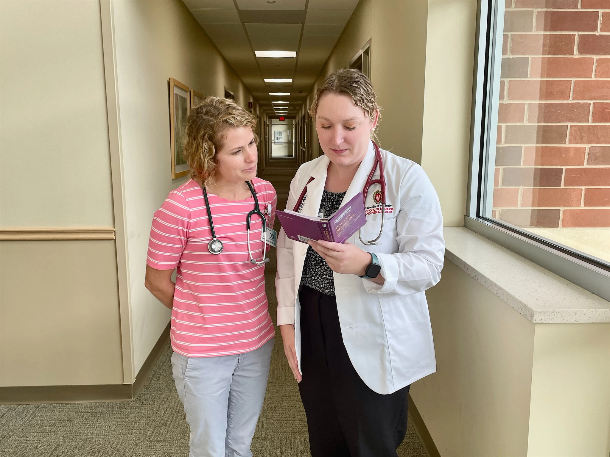 Medical student reviewing literature with doctor.