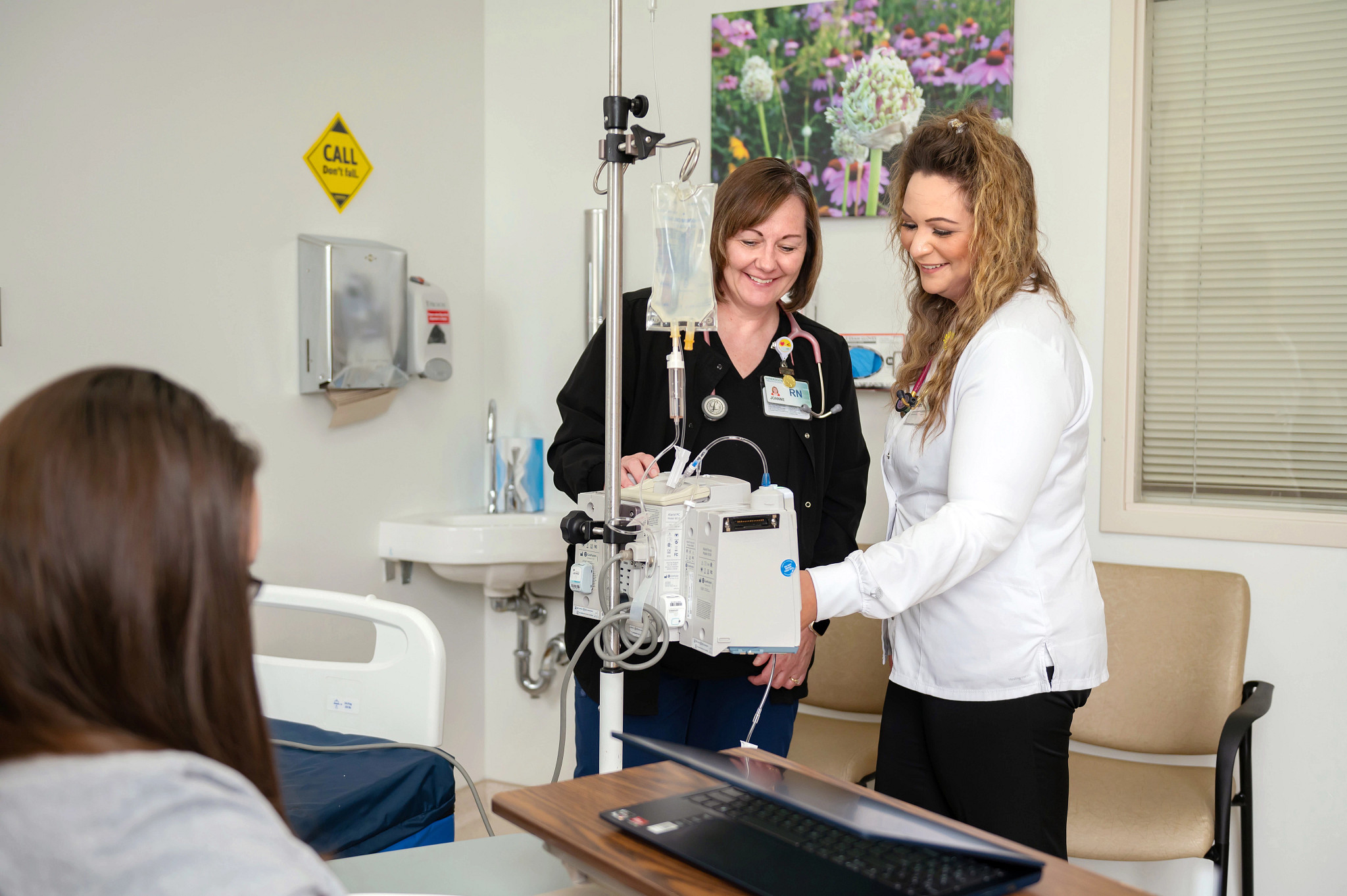 Registered nurse teaching new nurse about infusions.