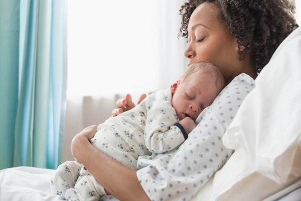 Mixed race mother holding newborn baby in hospital