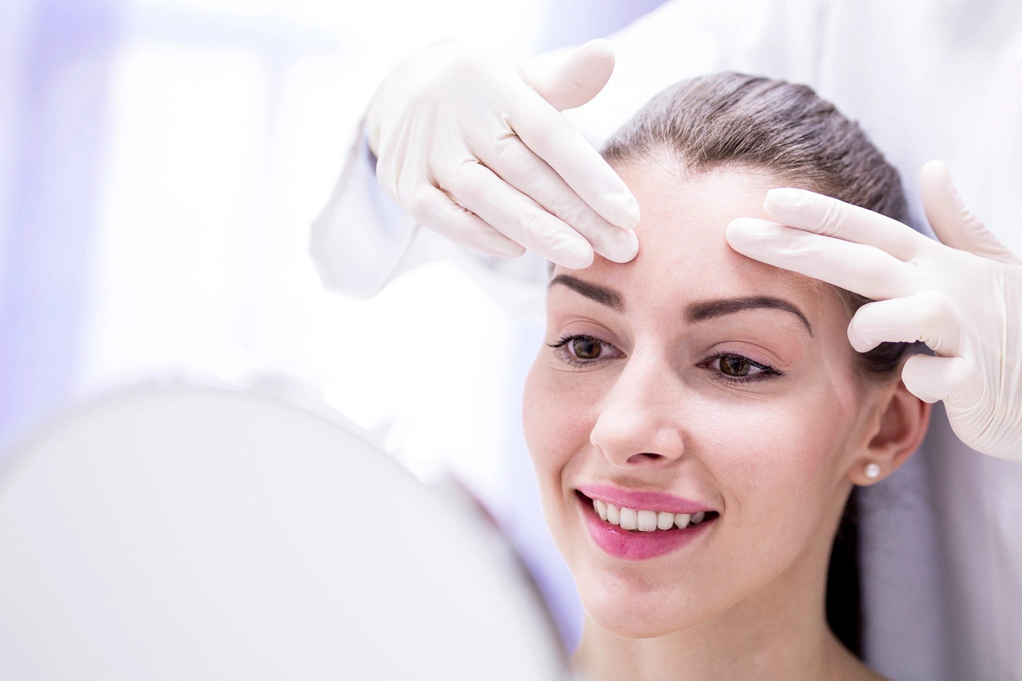 Doctor examining young woman's forehead