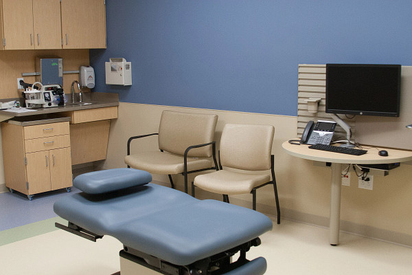 Patient exam room with table, chairs and workstation.
