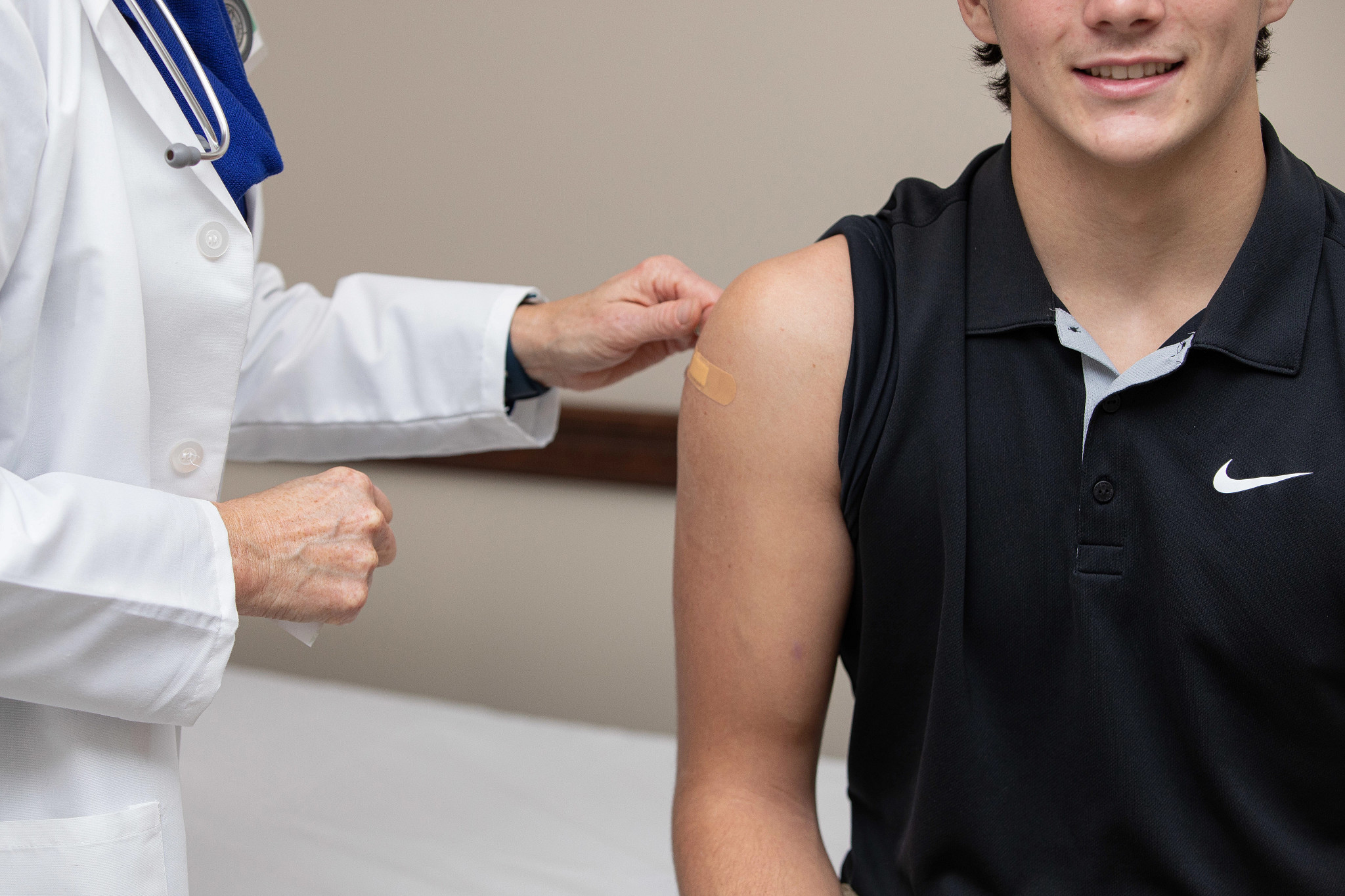Doctor placing bandaid on patient after shot.
