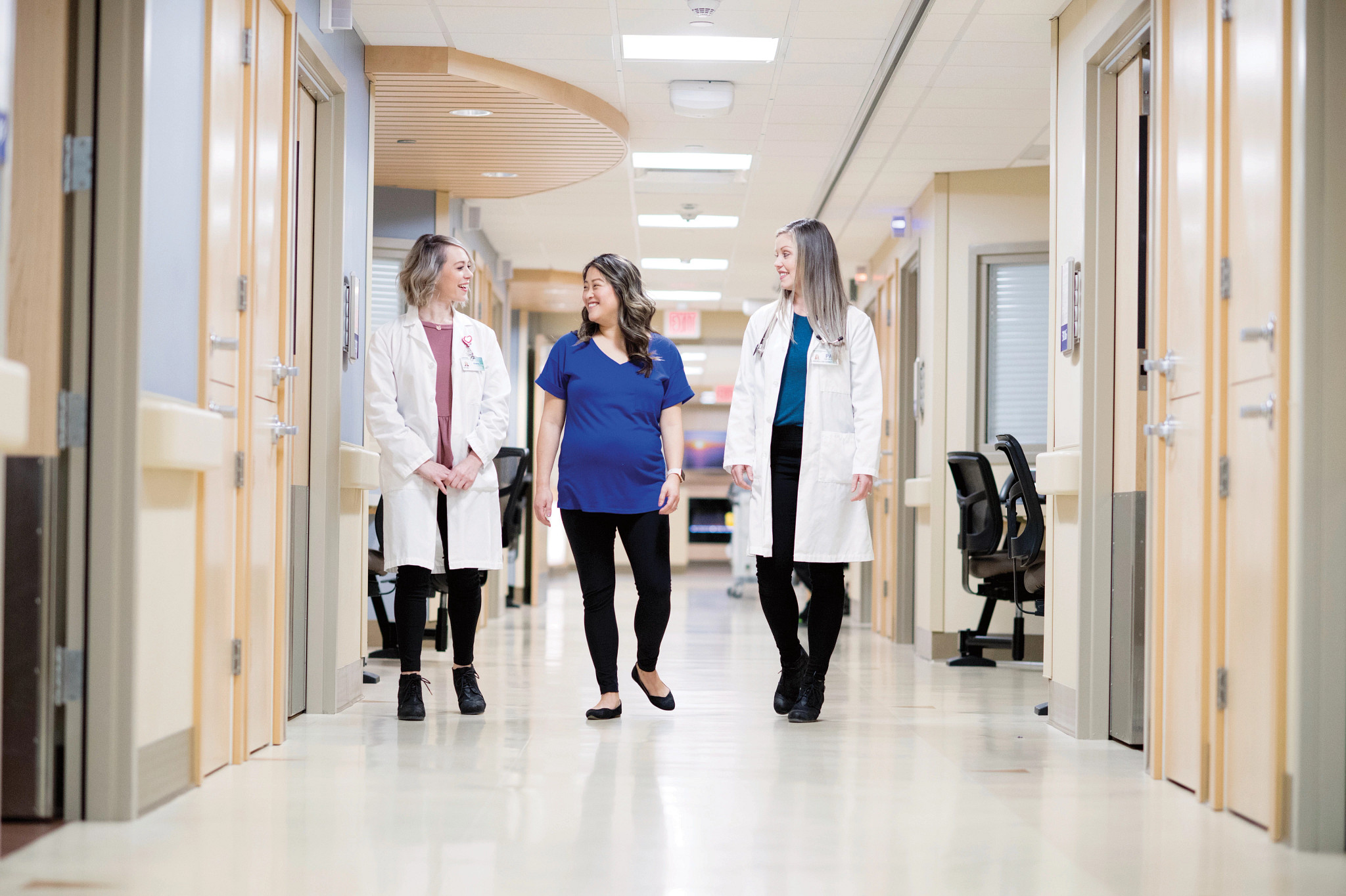 Pregnant woman walking between two healthcare providers.