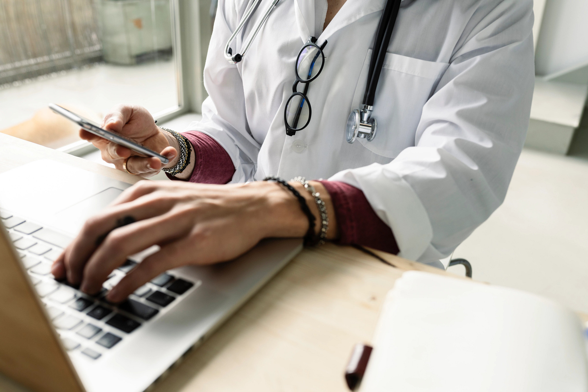 Close-up of a female doctor using computer and smartphone.