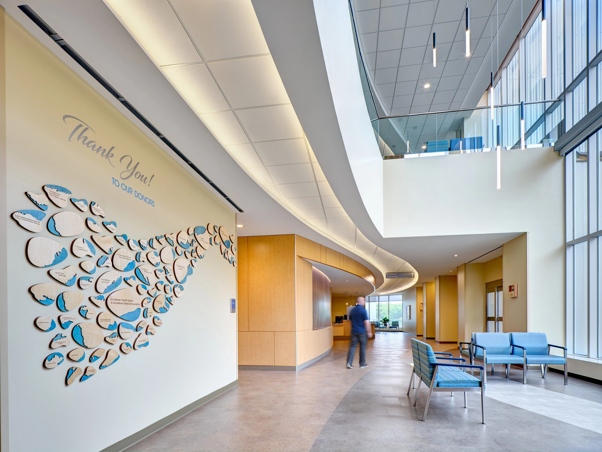 Patient walking through modern hospital lobby.