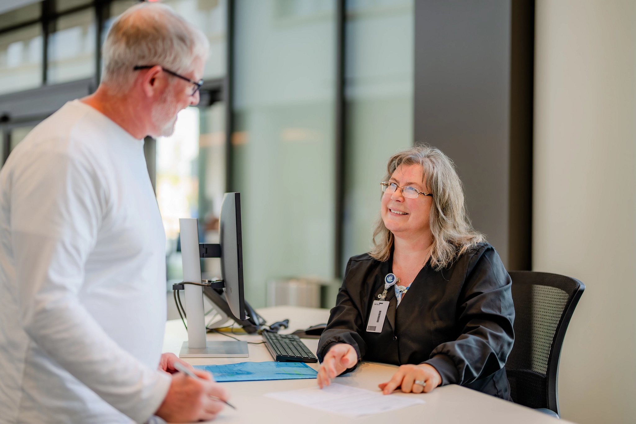 A male patient being greeted at a reception desk