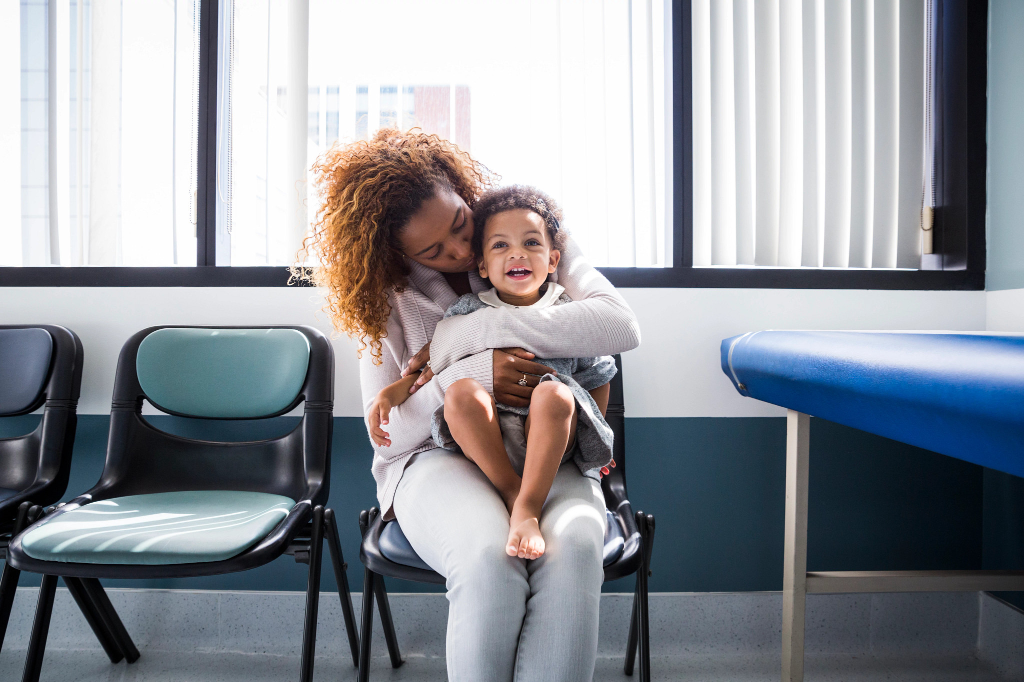 Woman with baby girl sitting in pediatrician waiting room